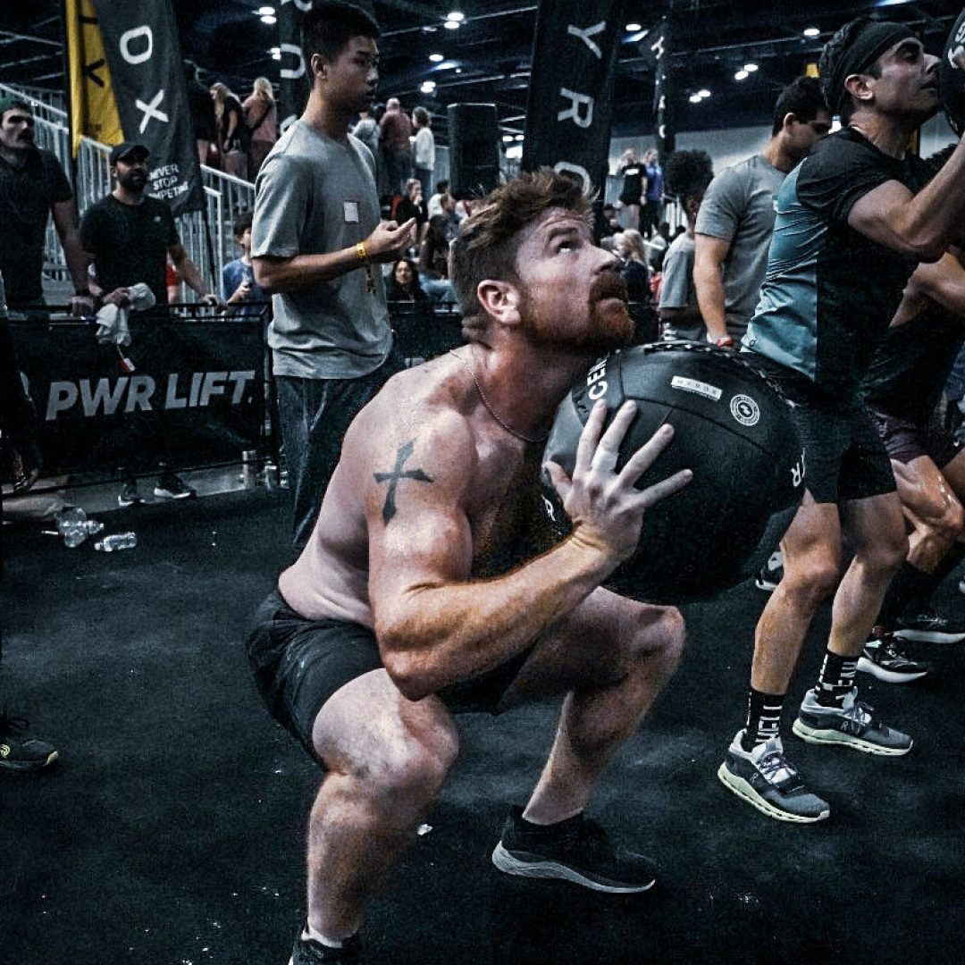 HYROX athlete carrying a wall ball into a squat during competition